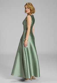 Abito lungo in satin, caratterizzato da un corpetto aderente e un colletto alto, in una tonalità di verde tenue con una finitura liscia e lucida.