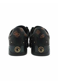 Para czarnych, pikowanych sneakersów z brązowymi, wzorzystymi zakładkami na piętach i złotymi, okrągłymi logo "G" na tylnych podeszwach, przedstawionymi z widoku tylniego.