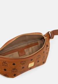Riñonera de cuero marrón con logotipos en relieve y patrón de diamantes, que cuenta con un cierre dorado y un interior beige. Los detalles incluyen un bolsillo para tarjetas.