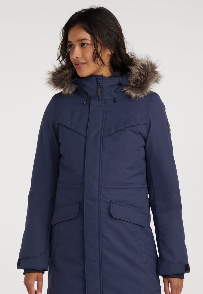 Marineblauwe parka met een capuchon gevoerd met nepbont, ritssluiting, twee voorkouden en een verstelbare capuchon met trekkoorden. Waterafstotend materiaal.