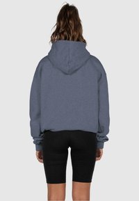 Felpa grigia con cappuccio, dallo stile rilassato, con un ampio cappuccio e maniche lunghe, abbinata a pantaloni bike neri. Tessuto morbido.
