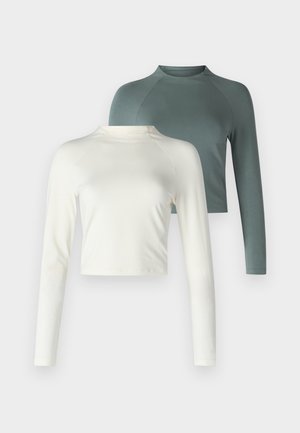 Kaksi pitkähihasta paitaa: yksi kermavärinen, lyhyempi malli ja toinen vihreä, normaali pituinen raglanhihoilla. Molemmat pehmeää kangasta.