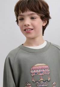 Lichtgroene sweatshirt met een groot, meerkleurig schedelmotief, gemaakt van zachte stof met een ronde hals en geribbelde manchetten.