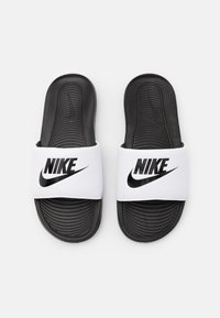 Fekete-fehér Nike papucsok, széles fehér pánttal, rajta a logóval, texturált fekete talppal és kontúrozott talpformával.