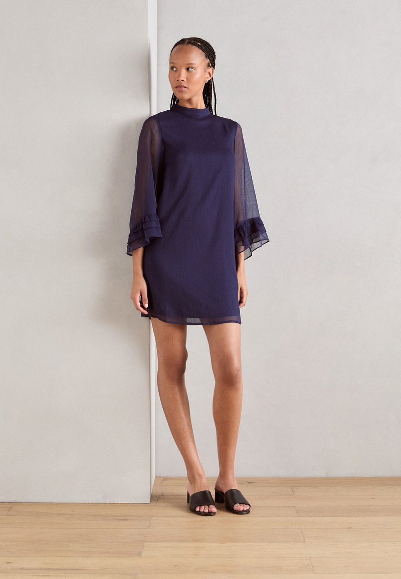 Navy blue dress with sheer, flared sleeves and a high neckline. The fabric has a soft texture, knee-length with ruffled sleeve accents.