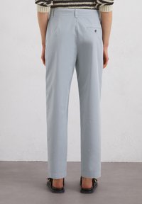 Pantalons bleu clair à coupe droite, dotés de poches latérales et d'une poche arrière unique. Tissu lisse avec une finition nette.