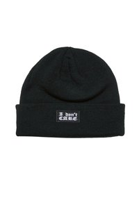 Juodas megztas beanie su juostos tekstūra ir sulenkta krašte, kurioje yra stačiakampis lopinėlis su balta užrašu "Man nerūpi".