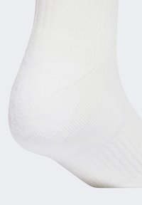 Biała bawełniana skarpeta sportowa o żebrowanej fakturze, z wzmocnionym piętą i palcami. Długość do połowy łydki, gładkie wykończenie, bez widocznych wzorów.