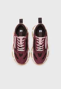 Zapatillas burdeos y marrones con cordones rosas, paneles de malla y una parte superior texturizada; cuentan con una suela gruesa y una lengüeta con tirador.