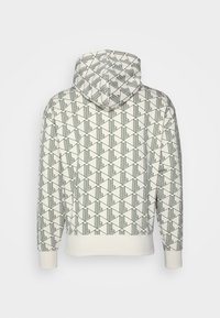 Valkoinen huppari, jossa on musta geometrinen kolmio- ja viivakuosi, ribbireunukset hihansuissa ja vyötäröllä, esitelty takaa yksinkertaisella taustalla.