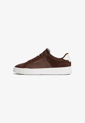 Sneaker marrone a basse top con suola bianca, chiusura con lacci e logo Tommy Hilfiger sul lato e sulla linguetta.