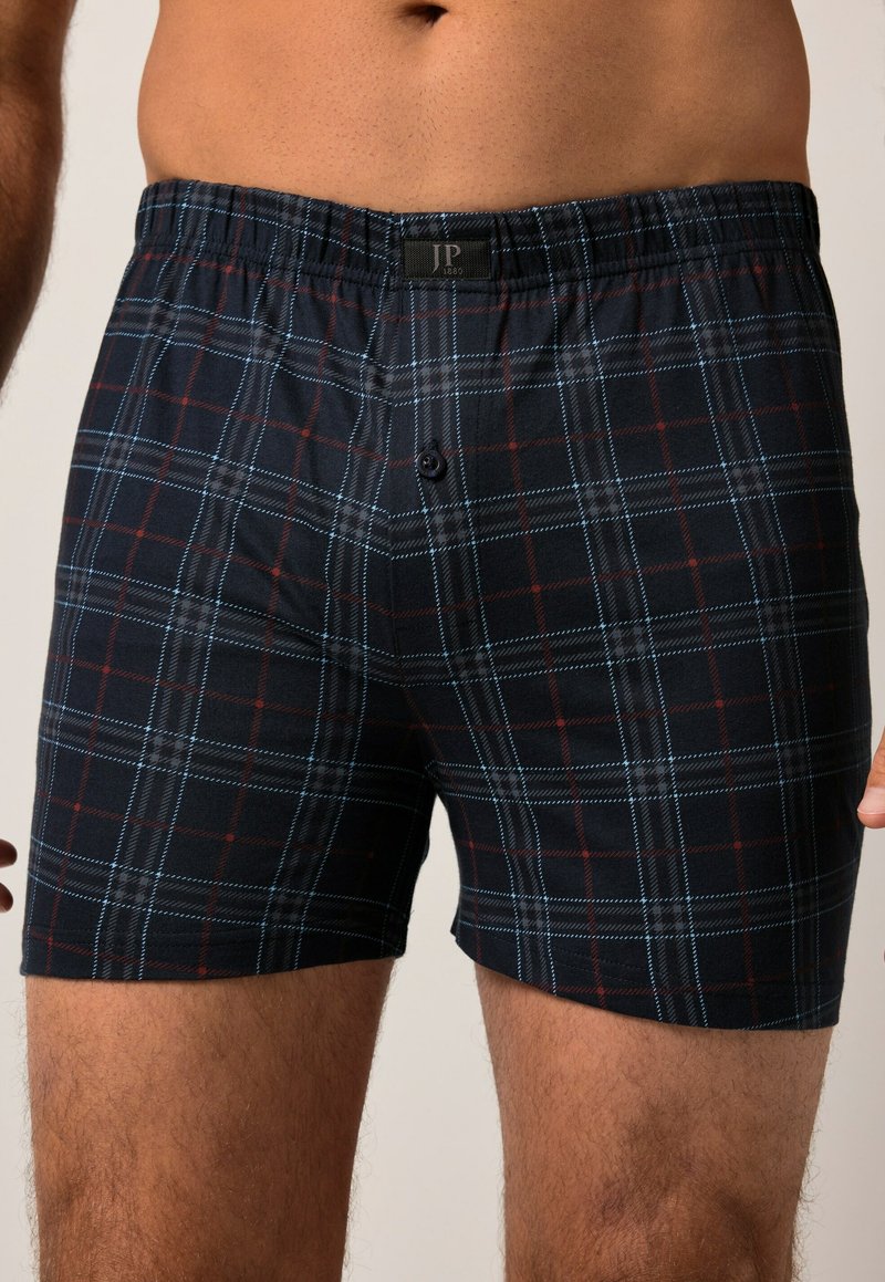 Boxers à carreaux noirs avec des motifs à rayures bleues et rouges, taille élastique et fermeture à un bouton. Fabriqués en coton.