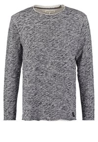 Pull à manches longues et col rond en tissu tricoté gris et noir chiné, avec une petite étiquette de marque près de l'ourlet.
