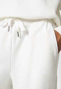 Witte katoenen joggers met een elastische tailleband met trekkoorden en twee zijzakken. Glad materiaal met minimalistische designdetails.