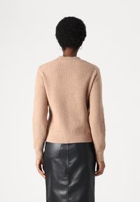 Helles rosa geripptes Sweatshirt mit langen Ärmeln und rundem Halsausschnitt, kombiniert mit einem schwarzen Lederrock mit gesticktem Einsatz.