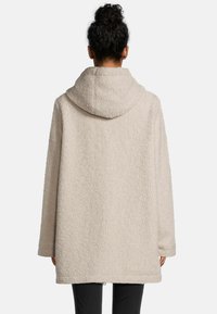 Cremefarbene Fleecejacke mit Kapuze, oversize Schnitt und strukturierter Oberfläche. Beeinhaltet lange Ärmel und einen Saum, der bis zur Mitte des Oberschenkels reicht.