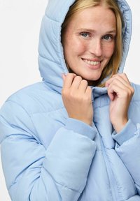 Svijetloplava puffer jakna s kapuljačom, sa kvadratnim uzorkom, rebrastim manžetama i prednjim zatvaračem na cipzar. Mekan materijal.