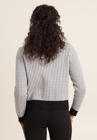 Pull en laine noir et blanc avec un motif en grille, doté d'un col rond et de poignets et ourlet côtelés. Design plus court et ajusté.