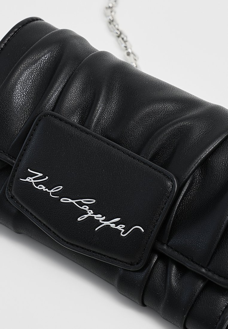 Pochette en cuir noir avec un design matelassé, dotée d'une plaque de logo en argent et d'une chaîne en argent pour le porter.