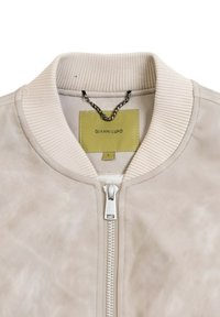 Giubbotto bomber beige chiaro realizzato in materiale testurizzato, con colletto a coste, chiusura con zip e un'etichetta nel colletto.