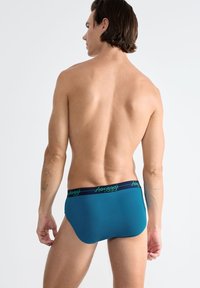 Tealfarbene Herrenunterhose mit weicher Textur, ausgestattet mit einem kontrastierenden, marineblauen Bund und grünem Logo. Der elastische Bund sorgt für einen sicheren Sitz.