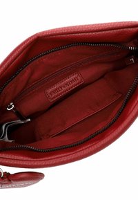 Red leather handbag interior with a zippered pocket. Soft fabric lining, one divider, and embossed logo on the side. Smooth texture.