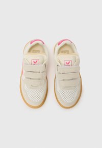 Hvite sneakers med rosa detaljer, laget av lær og semsket skinn. Har tre borrelåsremmer, perforert tå og såle av gummigummi.