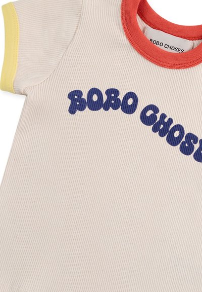 T-shirt a coste crema con accenti rossi e gialli, caratterizzato da un audace testo blu "BOBO CHOSES" sulla parte anteriore. Tessuto morbido e elasticizzato.