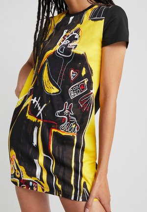 Sukienka z krótkim rękawem, charakteryzująca się żywym żółtym i czarnym wzorem z abstrakcyjnymi motywami, szkicowymi detalami oraz kontrastującymi akcentami kolorystycznymi.