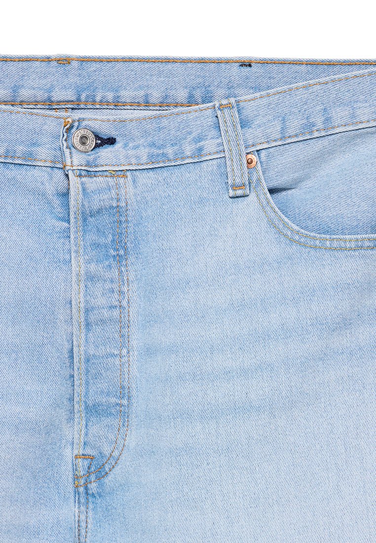 Jean en denim bleu clair avec une coupe classique, un léger délavage, quincaillerie en cuivre et coutures orange.