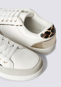 Sneakers bianchi con dettagli dorati e tallone in stampa leopardata. Presentano una tomaia in pelle liscia, una punta in suede testurizzato e lacci bianchi piatti.