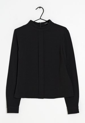 Maglia nera a maniche lunghe con colletto alto, dotata di chiusura con zip nella parte posteriore e di una delicata piega lungo la parte anteriore. Tessuto liscio e elastico.