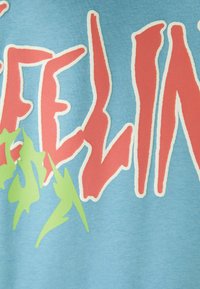 Tela azul con grandes letras rojas estilizadas contorneadas en blanco y dos diseños de rayos verdes superpuestos sobre la letra "E".