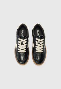 Black leather sneakers with cream laces and side stripe, round toe, rubber sole, minimalistic design, and padded collar.