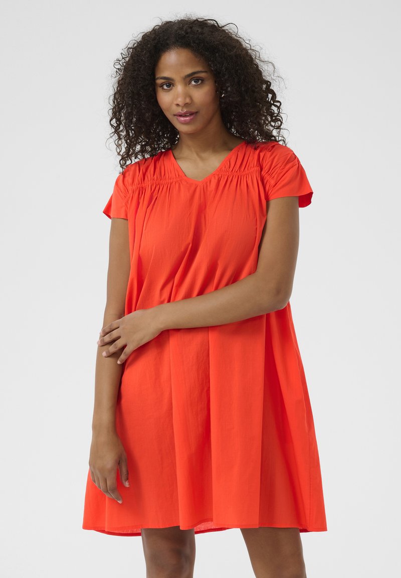 Kurzärmliges rotes Kleid mit V-Ausschnitt und Raffung an den Schultern, das einen lockeren Schnitt und eine glatte Textur aufweist.