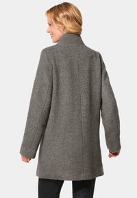 Gray wool coat with a high collar, long sleeves, straight cut, and textured finish. Features a clean design without visible fasteners.