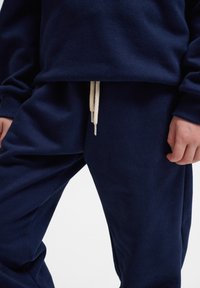 Felpa blu navy e pantaloni abbinati in felpa realizzati in tessuto morbido, con una vestibilità comoda e un cordoncino color crema in vita.