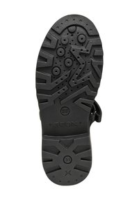 Semelle en caoutchouc noir avec un motif de traction, des protubérances circulaires et en forme d'étoile, et un logo de marque en relief "GEOX" avec des détails de brevet.