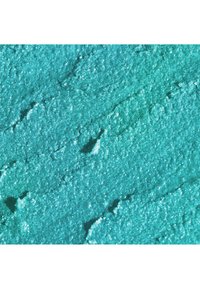 Polvere cosmetica turchese con finitura scintillante, presenta una superficie fine e strutturata e una profondità variabile creata da un'applicazione irregolare.