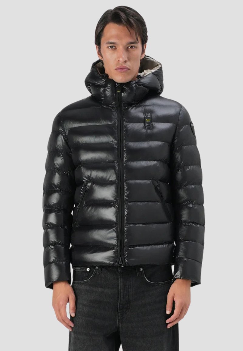 Giacca a vento nera con finitura lucida, dotata di zip frontale, cappuccio e tasche laterali. Design trapuntato con sezioni orizzontali ben evidenti.