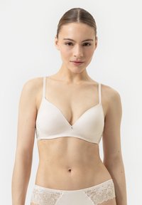 Soutien-gorge beige clair en tissu lisse, avec une bordure en dentelle à la base et des bretelles réglables. Présente un accent métallique subtil au centre.