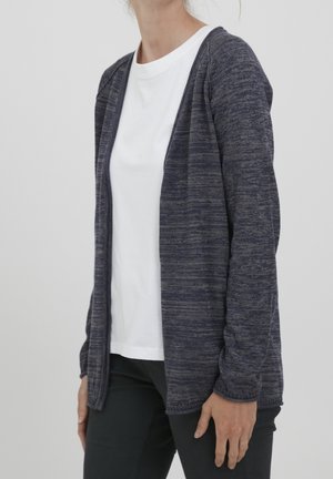 Navy blauwe cardigan met een textuur gebreid ontwerp, open voorkant en lange mouwen, gedragen over een witte T-shirt, met een relaxed fit.