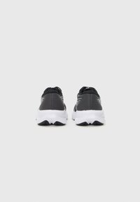 Black sneakers with a smooth synthetic upper and white soles. Features a padded collar and textured detailing along the sides.