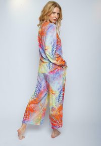 Buntes Loungewear-Set mit einem Langarmoberteil und einer Hose mit weitem Bein, mit wirbelnden Mustern in Orange, Blau und Gelb auf weichem Stoff.