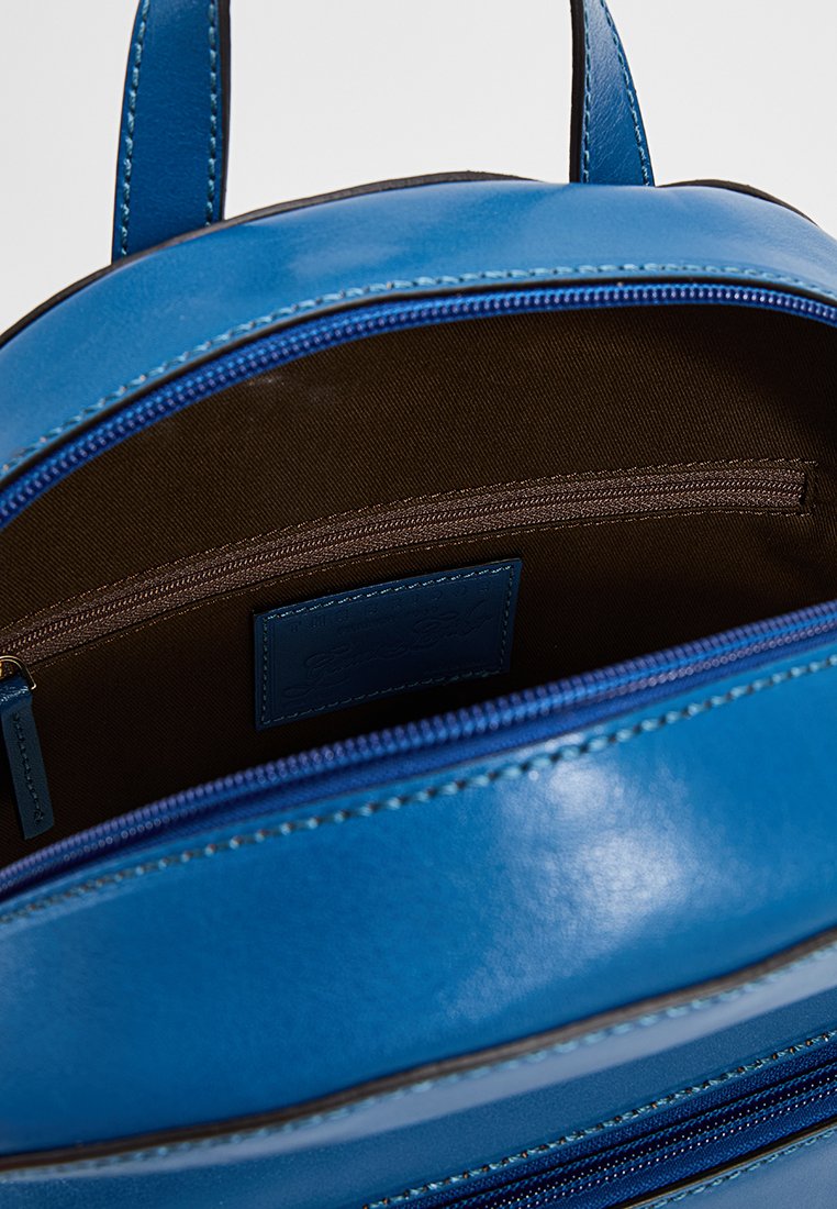 Zaino in pelle blu con apertura a zip, dotato di un interno in tessuto marrone, una tasca interna con zip e dettagli di cucitura a contrasto.