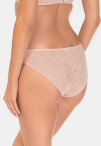 Koronkowe majtki w miękkim beżu, z kwiatowym wzorem, gładkimi krawędziami i średnim stanem dla komfortowego dopasowania. Teksturowane i delikatne.