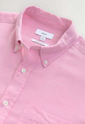 Světle růžová bavlněná košile s límcem na knoflíky, klasický střih, vybavená náprsní kapsou a bílými knoflíky. Štítek uvádí "NEXT" a velikost M.