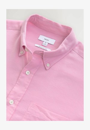 Cămașă din bumbac roz deschis cu guler butonat, croială regulară, având un buzunar pe piept și nasturi albi. Eticheta indică "NEXT" mărimea M.