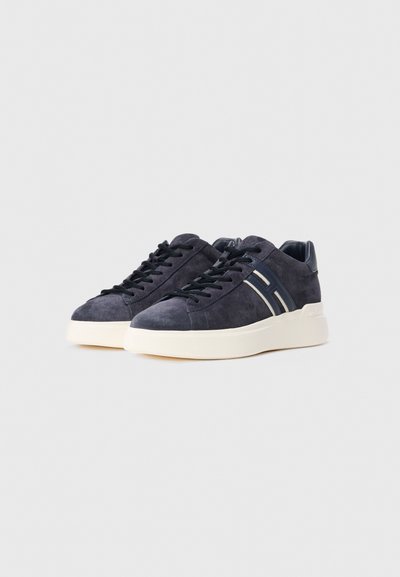 Pair of dark blue suede sneakers with black laces and white soles angled to the left on a plain light gray background.