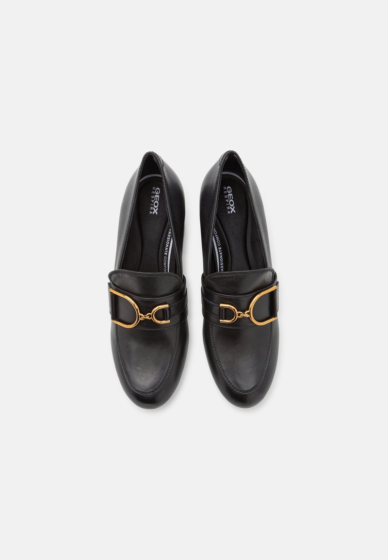 Schwarze Lederschuhe mit runder Zehenform, ausgestattet mit einem breiten Riemen und goldfarbene Hardware-Akzent über dem Spann. Glatte Textur, minimalistisches Design.